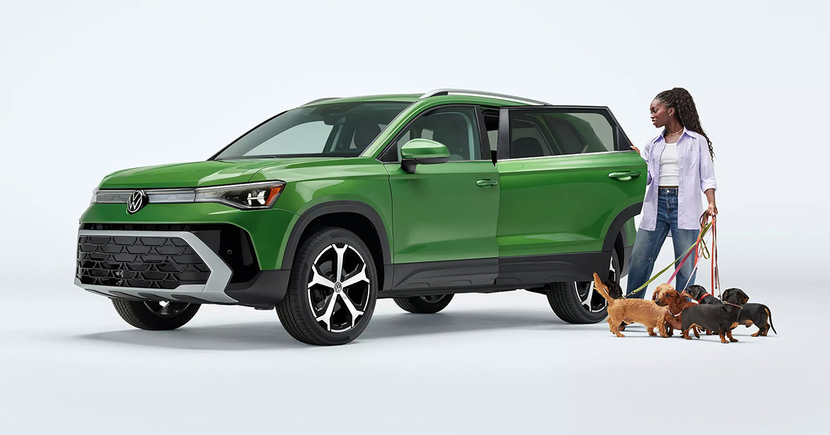 Green Volkswagen Taos with person walking dogs, highlighting family-friendly and adventurous vehicle design