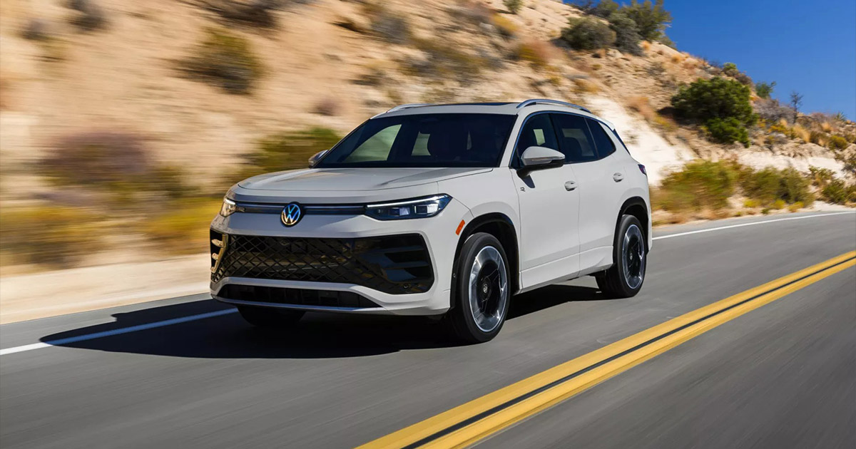 White Volkswagen ID.4 electric SUV driving on mountain road with rocky landscape in background