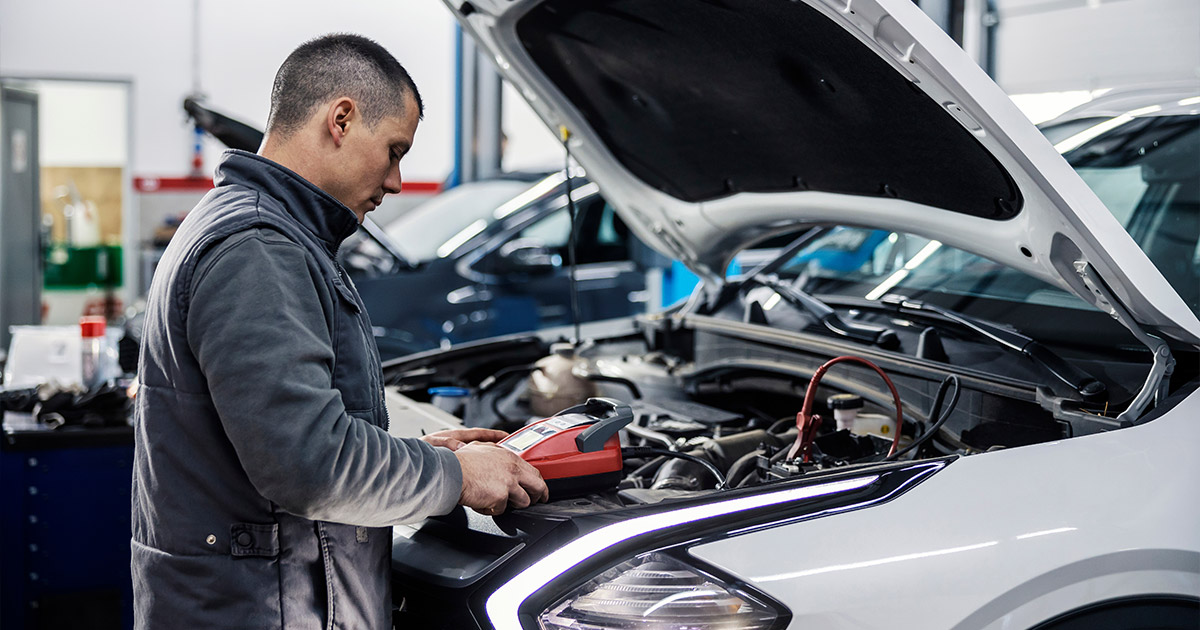 Automotive technician using diagnostic tool to service white Volkswagen in modern repair shop