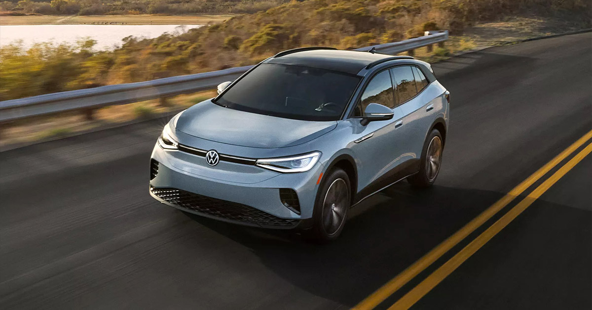 Blue Volkswagen ID.4 electric SUV driving on coastal highway with blurred natural background