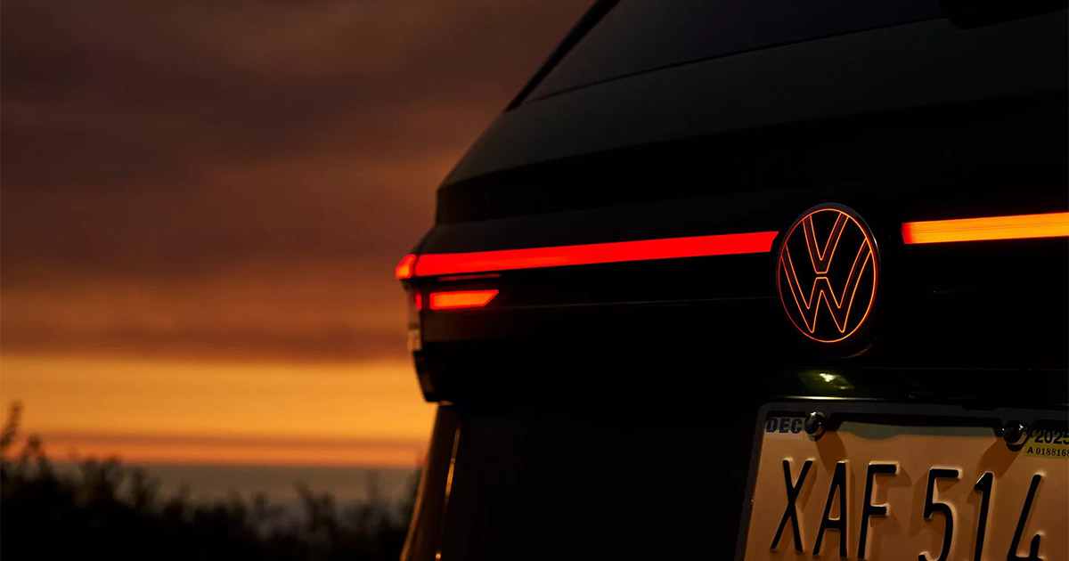 VW electric vehicle rear taillight with glowing red stripe at sunset, modern design with license plate visible